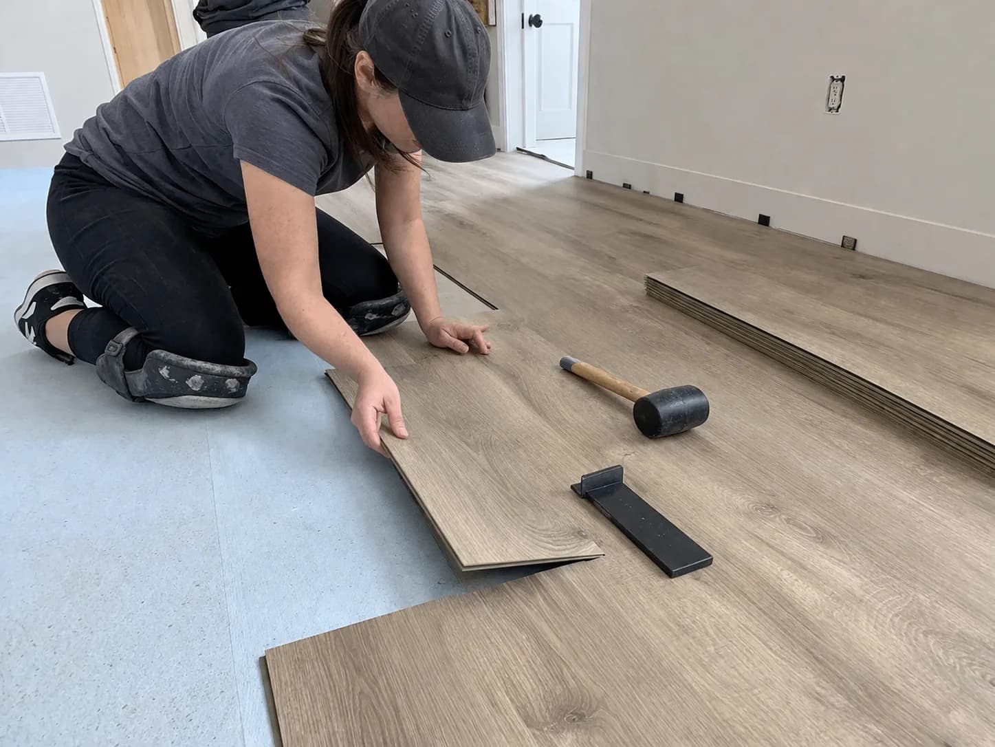 DIY installation of luxury vinyl plank flooring with click-lock planks being laid across a room
